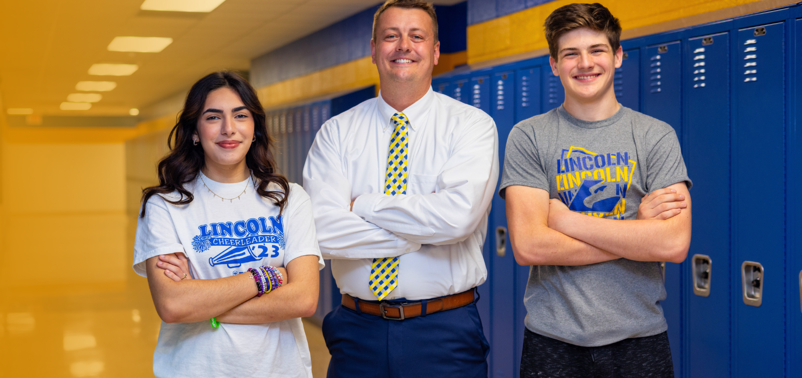 school superintendent stands with high schoolers in front of lockers