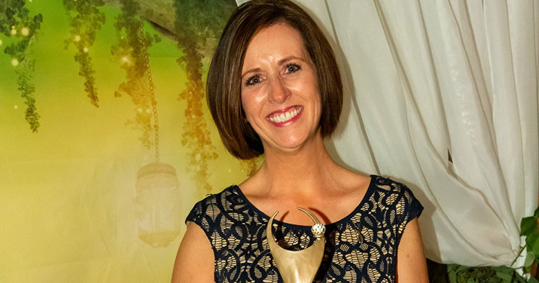 Melissa holding an ATHENA award.