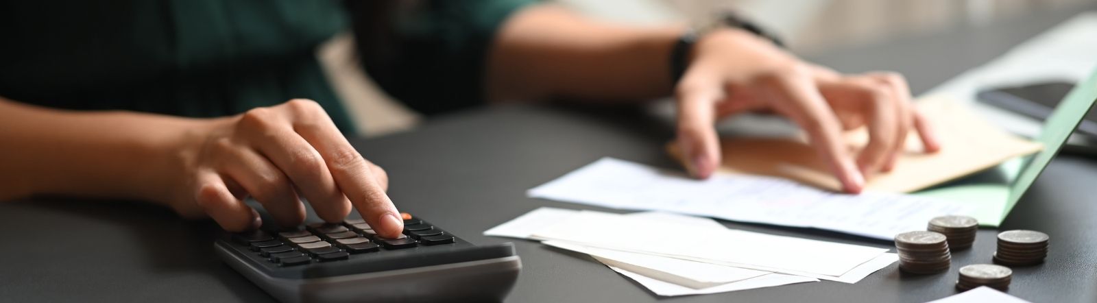 person using calculator and pointing at paperwork