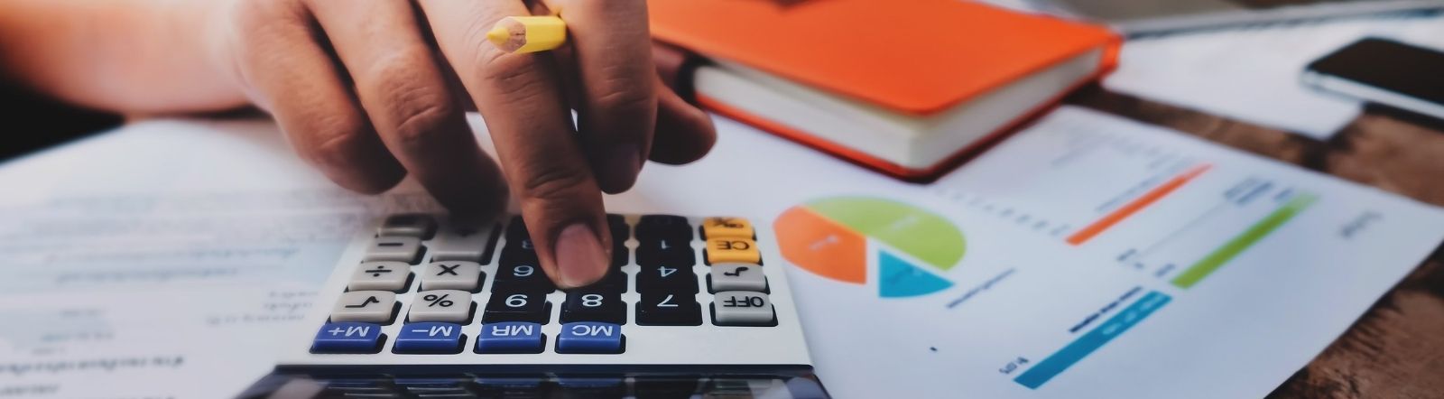 hand using calculator with financial paperwork
