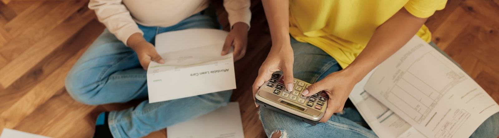 two people sitting on ground holding papers and calculator