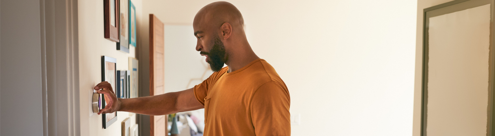 man adjusting wall thermostat